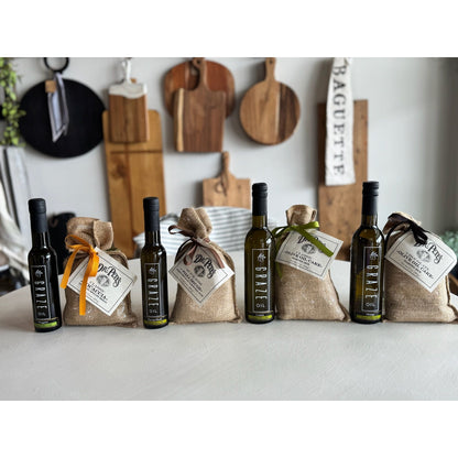 Bottles of Graze Oil olive oil with hessian bags and tags on a kitchen counter.