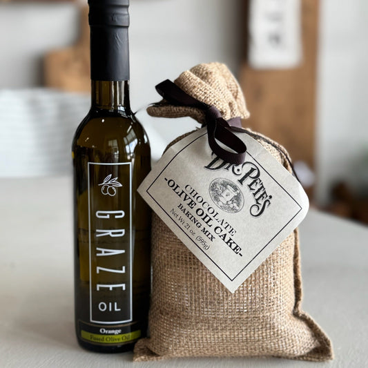 Bottle of Graze Oil and a bag of olive oil cake on a white surface.