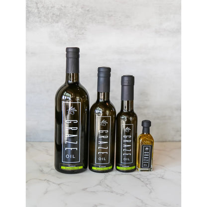 Four bottles of Graze Oil on a marble surface with a light gray background