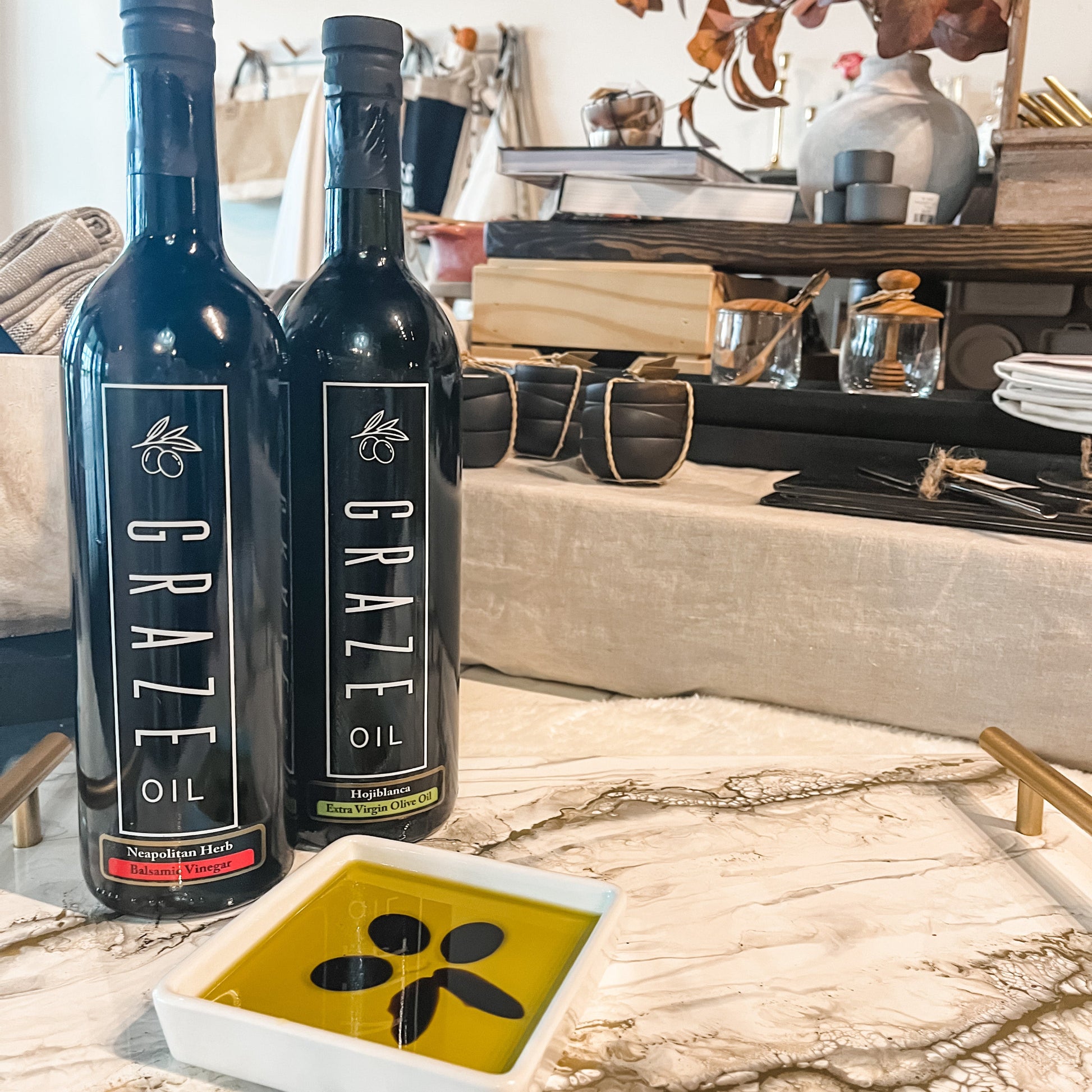 2 bottles of Graze Oil on marble table with dipping bowl