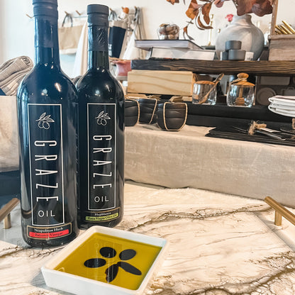 2 bottles of Graze Oil on marble table with dipping bowl