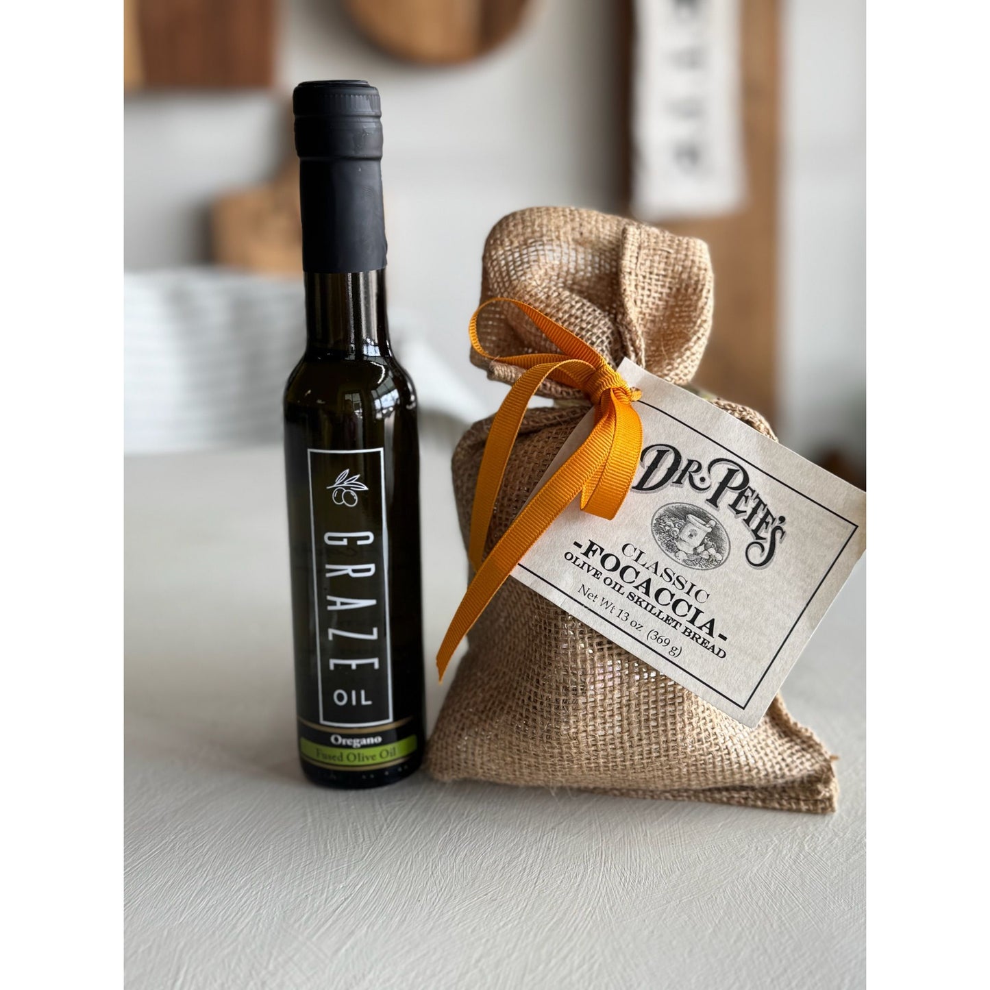 Bottle of Graze oil and a bag of Dr. Pete's focaccia mix on a light surface.