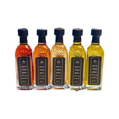 Five mini  bottles of Graze Oil with different colors on a white background