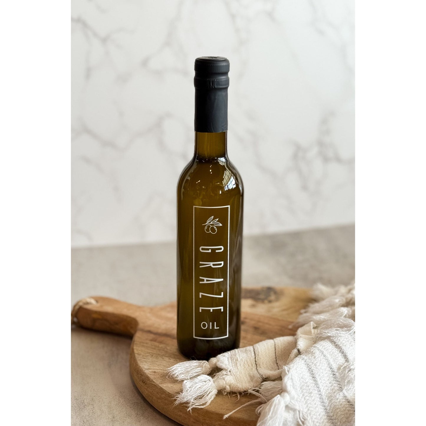 Bottle of Graze oil on a wooden board with a neutral background