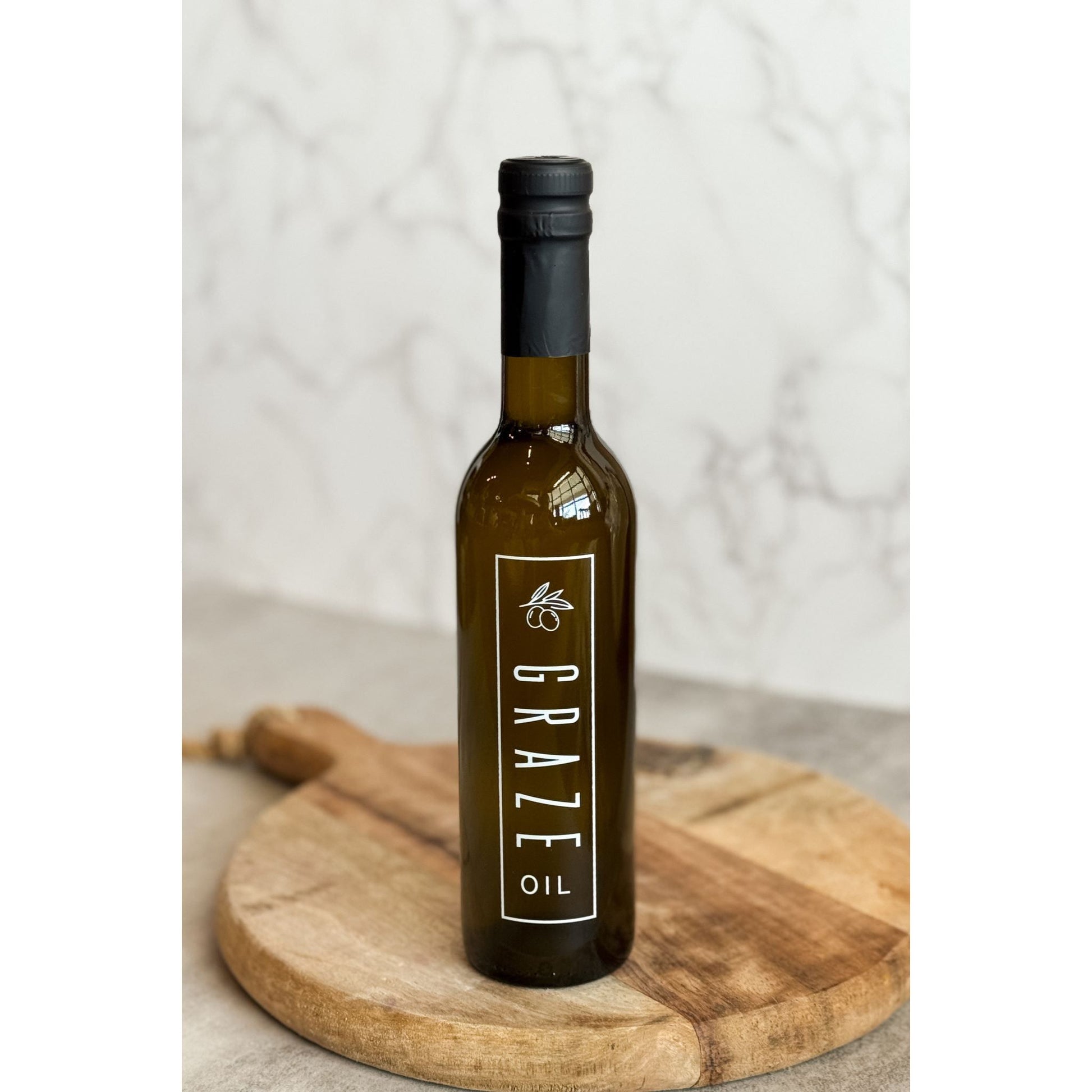 Bottle of Graze Oil on a wooden board with a neutral background