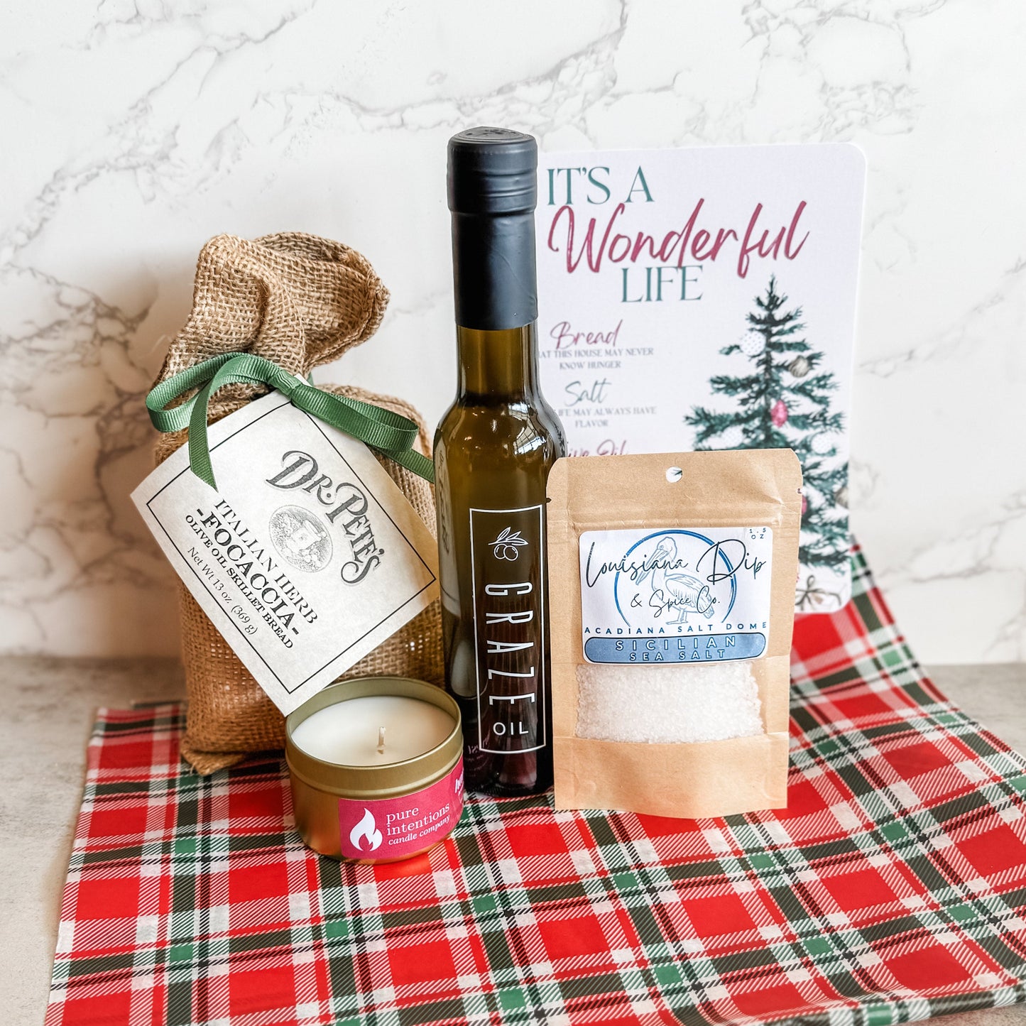 Gift set collection of items items including a Graze Oil bottle, bread mix in burlap bag with bow, candle, salt 