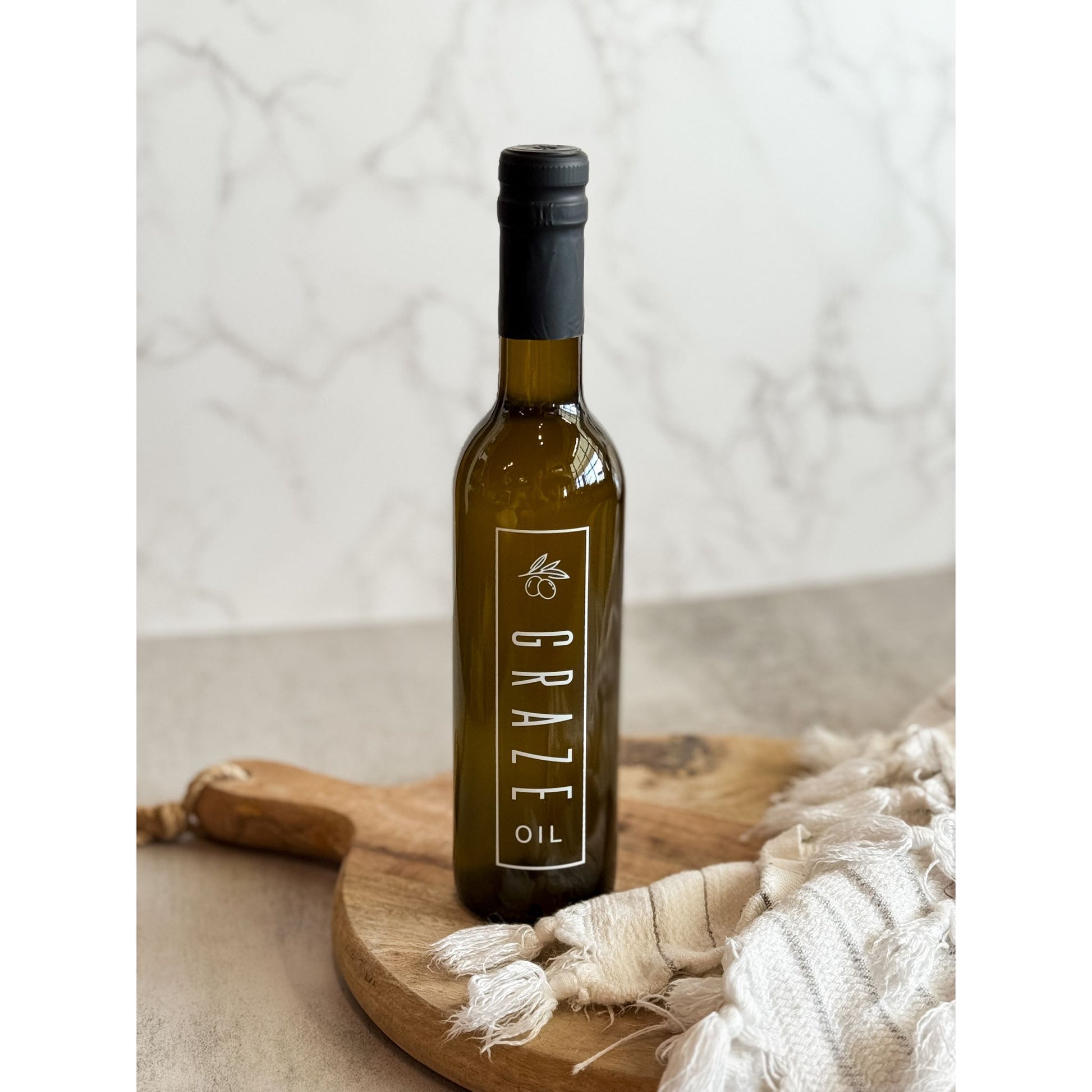 Bottle of Graze oil on a wooden board with a neutral background